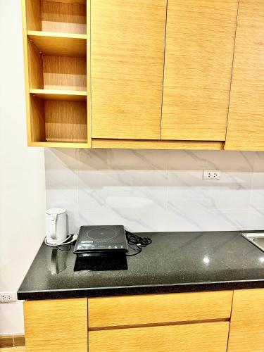 a kitchen with a black counter top and wooden cabinets at TMS Quy Nhơn - Hupa Apartment View Biển in Quy Nhon