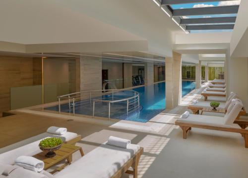 a swimming pool in a building with white furniture at Movenpick Living Istanbul West in Istanbul
