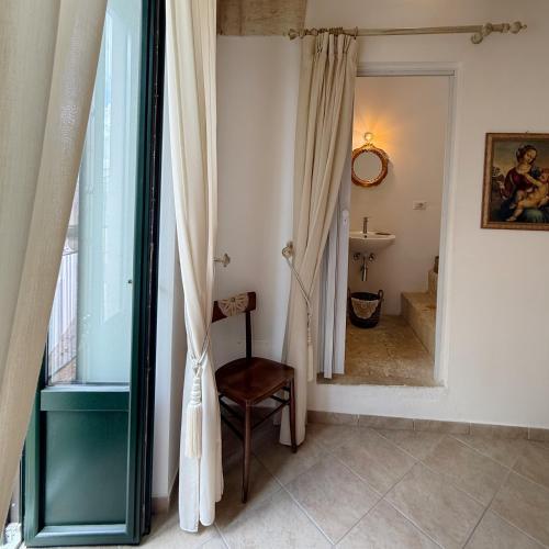 a bathroom with a mirror and a chair and a sink at Dimora Santa Domenica in Scorrano