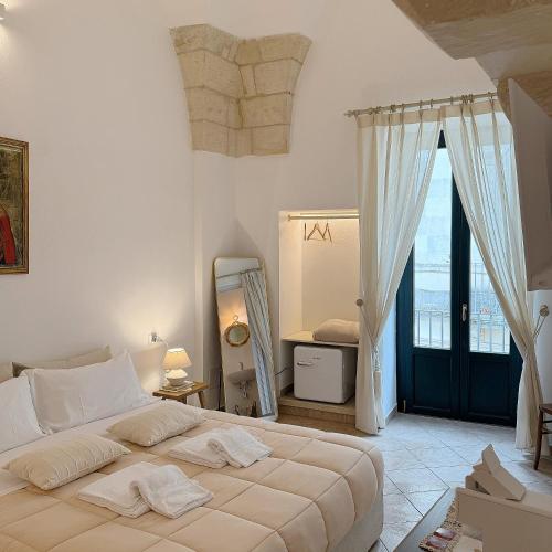 a white bedroom with a large bed and a window at Dimora Santa Domenica in Scorrano