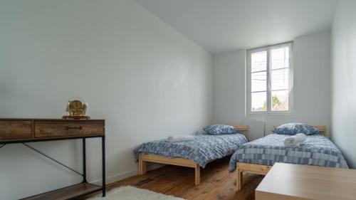 une chambre avec deux lits, une table et une fenêtre dans l'établissement Le Nid des Châtelains, à Lignières-Châtelain