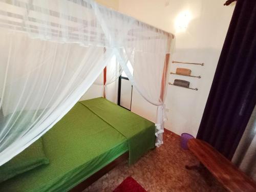 a small green bed in a room with a window at Bluebell Villa Mirissa in Kamburugamuwa