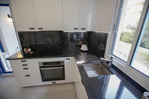 La cuisine est équipée de placards blancs, d'une cuisinière et d'un évier. dans l'établissement With balcony Near La Pointe De La Croisette, à Cannes