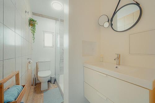 une salle de bain avec toilettes, lavabo et miroir dans l'établissement Le cocon logement pour 6 et 1 bébé, à Villeurbanne