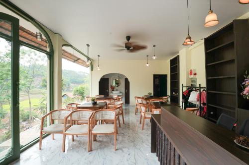 a dining room with tables and chairs and windows at Bamboo Hill Resort in Hữu Lũng