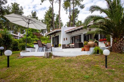 a white house with an umbrella in the yard at The Gift Sani Villa in Sani Beach
