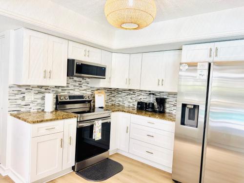 a kitchen with white cabinets and a stainless steel refrigerator at Tampa Luxury 5BR Estate with Pool and Golf Views in Tampa