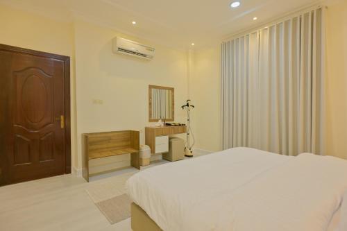 a white bedroom with a bed and a mirror at RJ's - Beautiful 3 Bedroom Apartment in Al Khobar