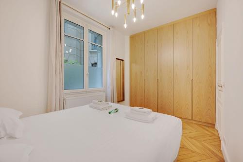 une chambre blanche avec un grand lit blanc et une fenêtre dans l'établissement Superb apartment with terrace 2BR 4P Trocadero, à Paris