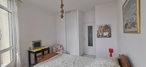 a bedroom with a bed and a desk and a television at T3 lumineux, vue mer, 74m2 in Clohars-Carnoët