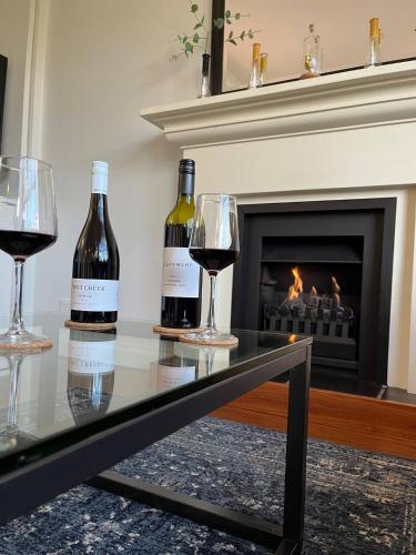 two bottles of wine sitting on a table in front of a fireplace at Villa Above Par, Privately Managed within Cypress Lakes Resort, Premier 2 Storey Villa, 2 Bedrooms, both with Private Ensuites, Light Breakfast included in Pokolbin