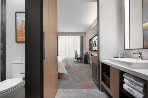 a bathroom with two sinks and a desk in a room at Hampton by Hilton Shanghai North Bund Siping Road in Shanghai