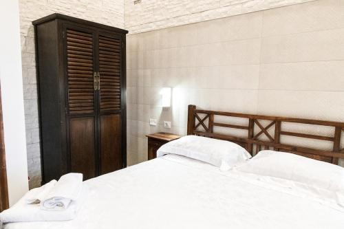 a bedroom with a white bed and a wooden cabinet at Villa Adele Eleganza & Comfort in Pachino