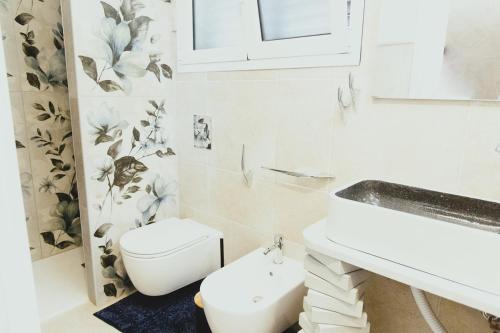 a white bathroom with a toilet and a sink at Villa Adele Eleganza & Comfort in Pachino