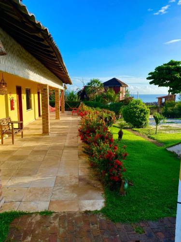 a porch of a house with flowers in the yard at Pousada La Ilha in Cajueiro