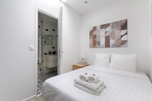 une chambre avec un lit blanc avec des serviettes dessus dans l'établissement Daumesnil Gare de Lyon II Appartement Cosy 1BR, à La Celle-sous-Gouzon