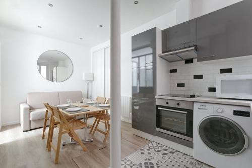 une cuisine et une salle à manger avec une table et un lave-linge dans l'établissement Daumesnil Gare de Lyon II Appartement Cosy 1BR, à La Celle-sous-Gouzon