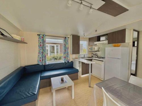 un salon avec un canapé bleu dans une cuisine dans l'établissement Camping 3 étoiles - ccbbe0c, à Sigean