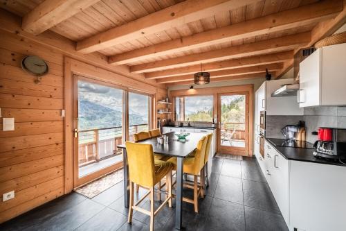 une cuisine avec une table, des chaises et des fenêtres dans l'établissement Chalet Célestine 7ch - '4 sdb', à Verchaix