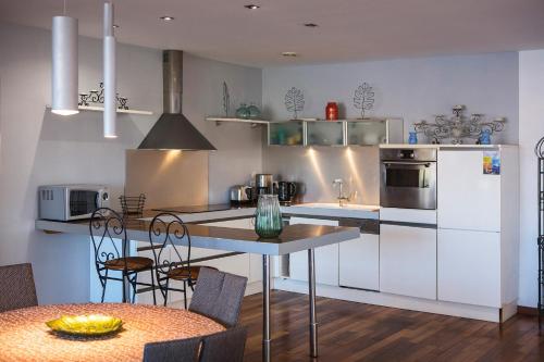 une cuisine avec des appareils blancs et une table avec des chaises dans l'établissement Hotel Le Bon Port, à Collioure