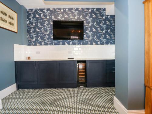 a living room with blue walls and a flat screen tv at Fir Grove in Menai Bridge