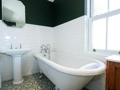 a white bathroom with a tub and a sink at Fir Grove in Menai Bridge