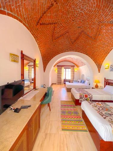a large room with two beds and a television at Beach safari nubian resort in Marsa Alam City