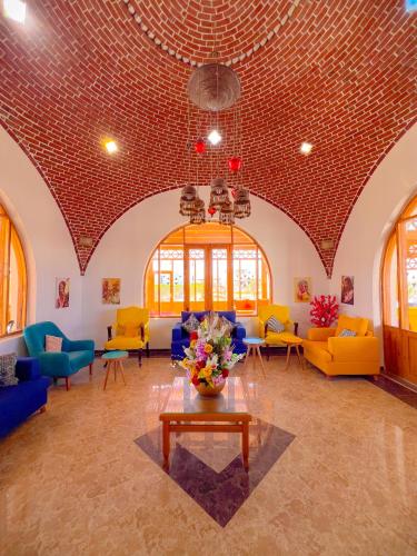 a living room with yellow and blue furniture and a brick ceiling at Beach safari nubian resort in Marsa Alam City