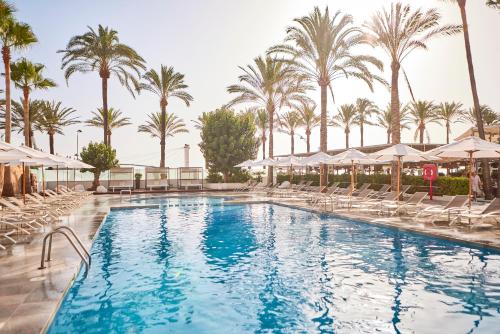 a swimming pool with chairs and palm trees at Hotel Playa Golf - Adults Only in Playa de Palma