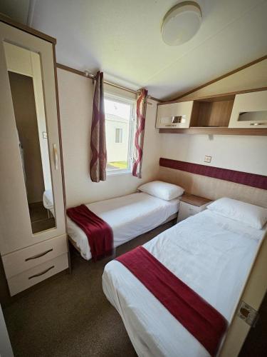 a small room with two beds and a window at Modern caravan Robin Hood Rhyl in Rhyl