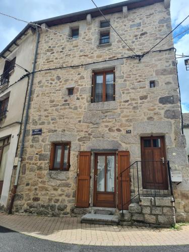 a stone building with wooden doors and windows at Studio AL'escapade in Saint-Chély-dʼApcher