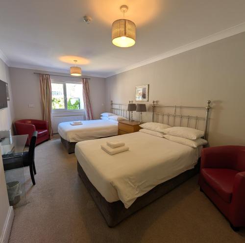 a hotel room with two beds and a red chair at The White Rock Hotel in Hastings