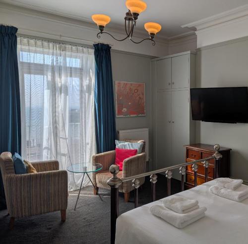 a bedroom with a bed and chairs and a window at The White Rock Hotel in Hastings
