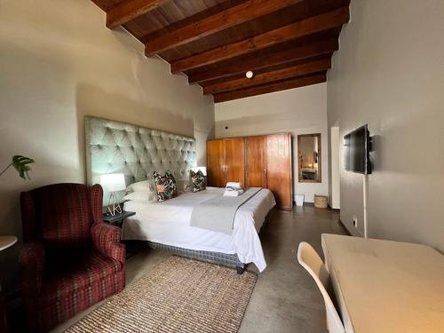 a bedroom with a large bed and a chair at Avignon Guesthouse in Worcester