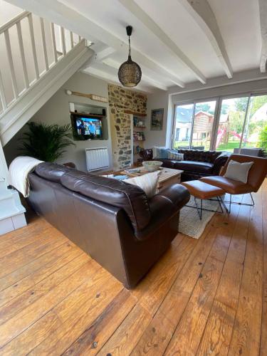a living room with a leather couch and a tv at Emerald Coast Gites and Lodge in Hénansal
