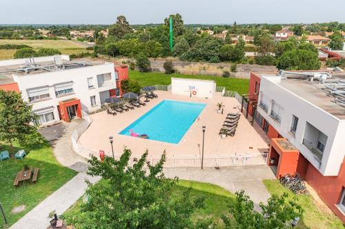 - une vue sur la piscine en face d'un bâtiment dans l'établissement Appart'City Confort Toulouse Aéroport Cornebarrieu, à Cornebarrieu