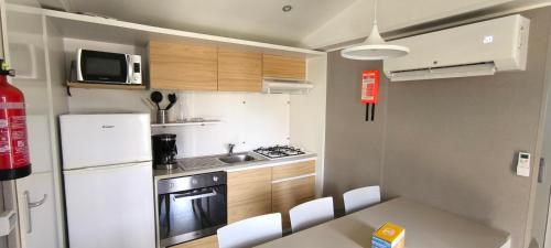 a small kitchen with a white refrigerator and a table at Houlgate-154- Mobilhome cosy 4 personnes Camping 5 étoiles in Houlgate