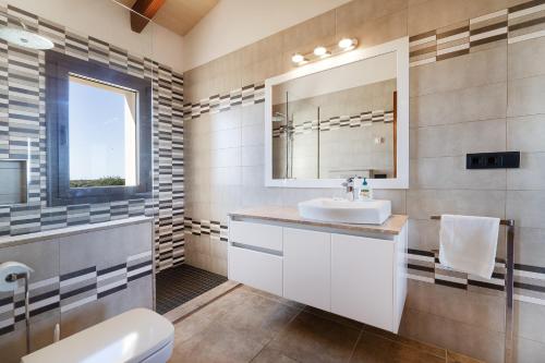 a bathroom with a sink and a toilet and a mirror at Finca Sa Pletassa, 8 pax wifi piscina jardín BBQ in S'Horta
