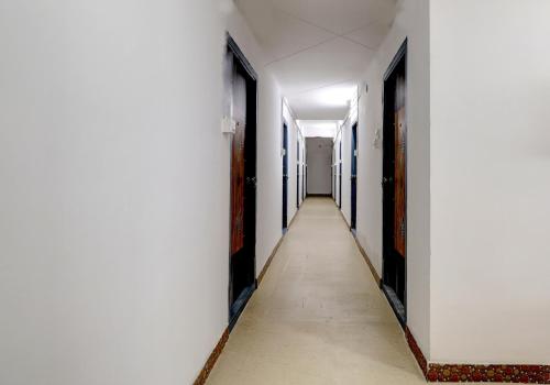 un pasillo vacío en un edificio de oficinas con paredes blancas y un pasillo largo en Hotel O HR, en Kundakal