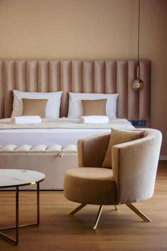 a bedroom with a bed with a couch and a chair at Palazzo Apartments in Rimavská Sobota