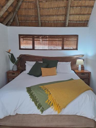 a bedroom with a white bed with a yellow and green blanket at LittleBush Private Lodge in Hoedspruit