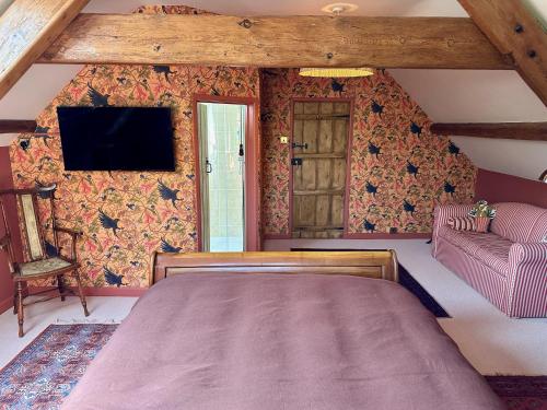 a bedroom with a bed and a tv on a wall at The Old Forge B&B and Glamping in Compton Abbas
