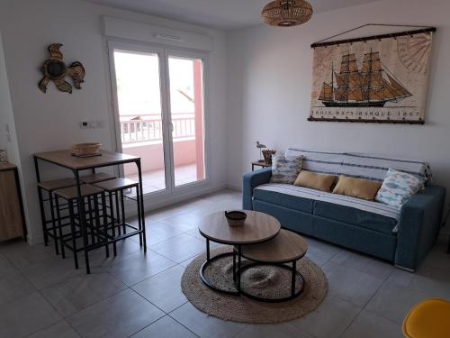 un salon avec un canapé bleu et une table dans l'établissement Studio tout neuf, tout équipé, à 2 pas de l'océan, à Biscarrosse