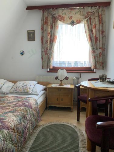 una camera da letto con un letto, un tavolo e una finestra di Pokoje u Zofii a Ząb