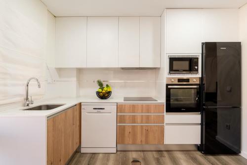 a kitchen with white cabinets and a black refrigerator at Spacious & Stylish Flat with Garage by HostWise in Ermesinde