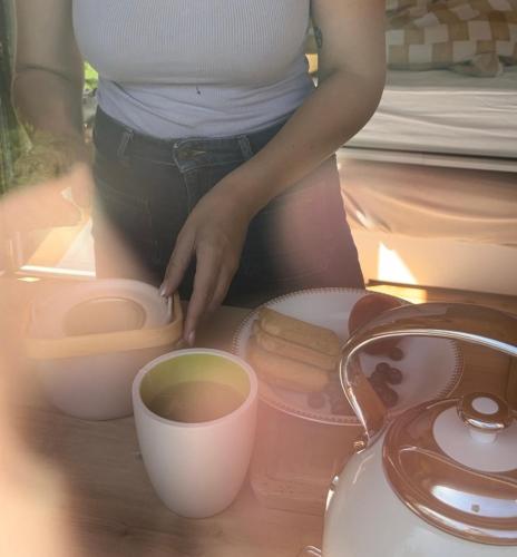 une femme se tient à côté d'une tasse de café dans l'établissement Les cabanes de Julie, à Lissac et Mouret