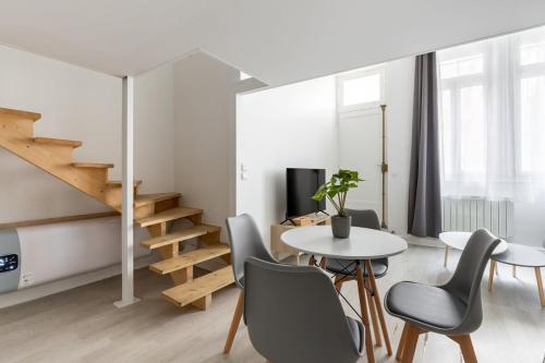 un salon avec une table et des chaises et un escalier dans l'établissement Appartement Duplex proche de l'Arc de Triomphe et Trocadero, à Paris