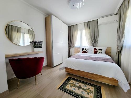 une chambre avec un grand lit et une chaise rouge dans l'établissement Villa Riviera, à Saint-Paul-de-Vence