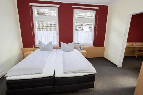 a bedroom with two beds and two windows at Hotel Zur Linde in Meldorf