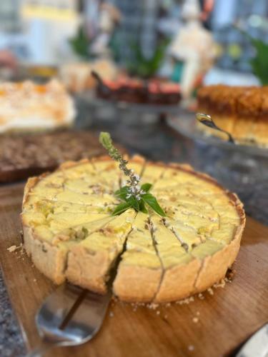 a pie on a wooden cutting board with a sprig ofilantro on top at Pousada Brisa do Mar in Torres
